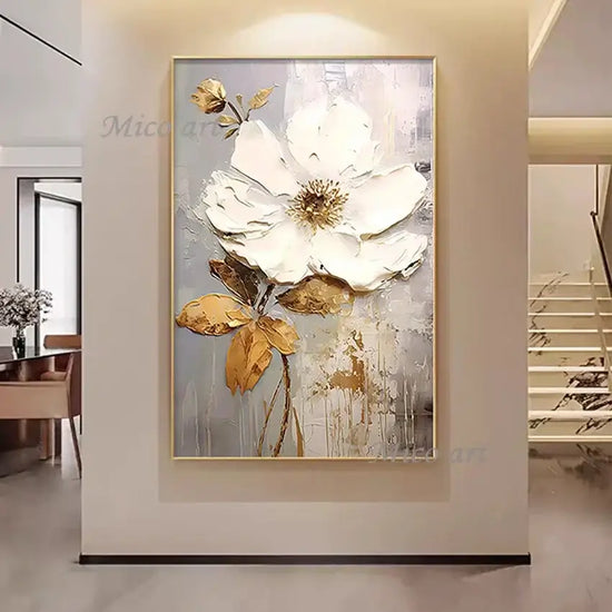 Framed abstract floral artwork with white and gold flowers on a wall.