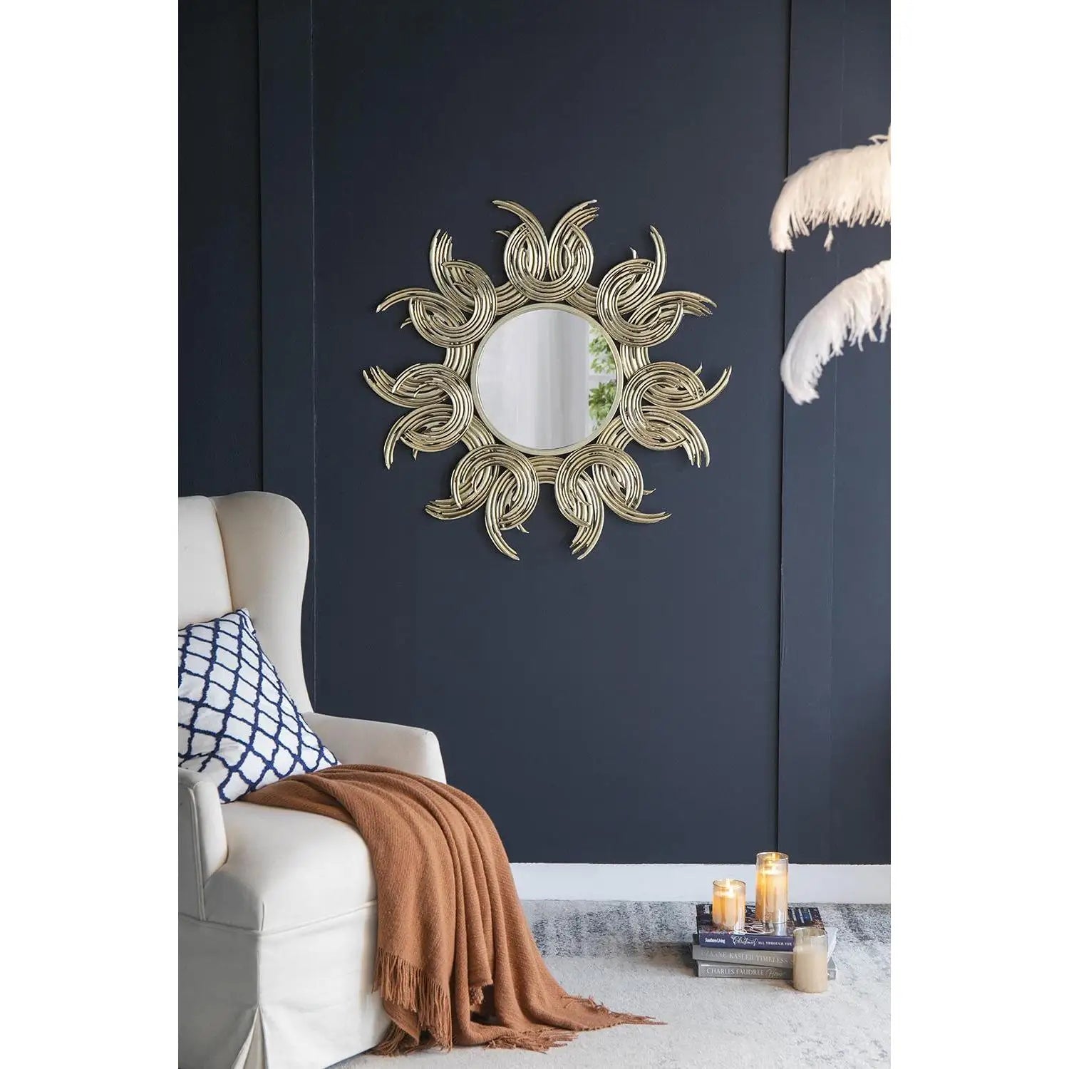 Decorative wall mirror with sun design on a dark blue wall above a white chair.
