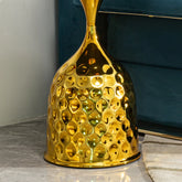 Gold textured vase on a marble surface with a blue cushioned chair in the background