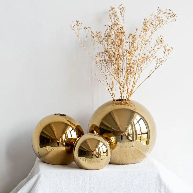 Three gold metallic vases with a white background