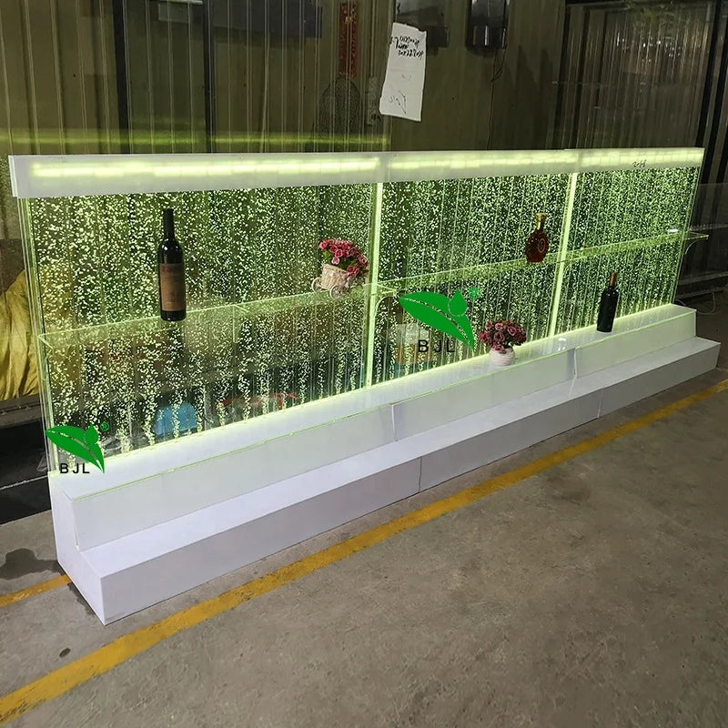 Acrylic water bubble bar cabinet with illuminated shelves, featuring 16-color LEDs, displaying bottles and decor.