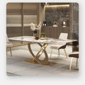A modern dining table with a white marble-patterned top and a sculptural gold base, styled in a contemporary dining room with matching chairs and warm ambient lighting.