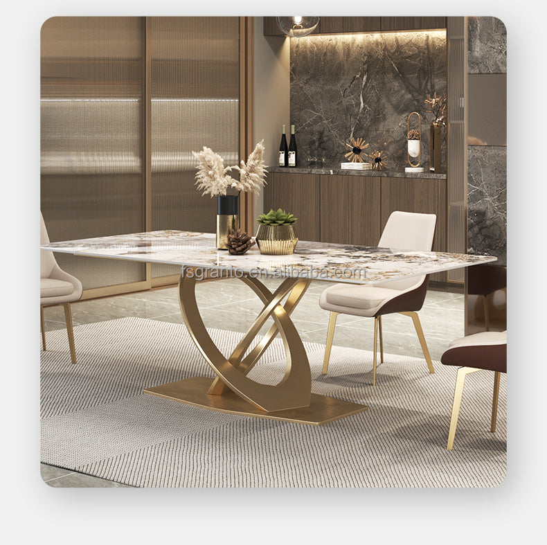 A modern dining table with a white marble-patterned top and a sculptural gold base, styled in a contemporary dining room with matching chairs and warm ambient lighting.