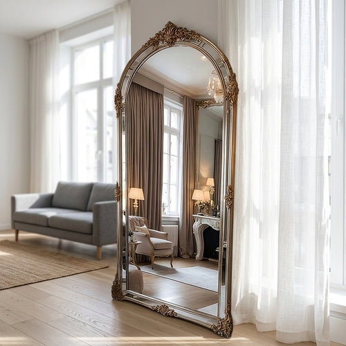 Aurelie ornate arched floor mirror beautifully displayed in a bright, elegant living room setting.