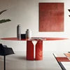 Modern dining room with a red table and chairs against a white wall.