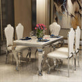 Modern minimalist marble dining table set with elegant white chairs and floral centerpiece.