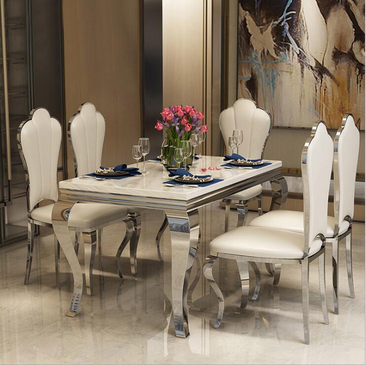 Modern minimalist marble dining table set with elegant white chairs and floral centerpiece.