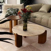 Round wooden coffee table with a vase of flowers in a living room setting.