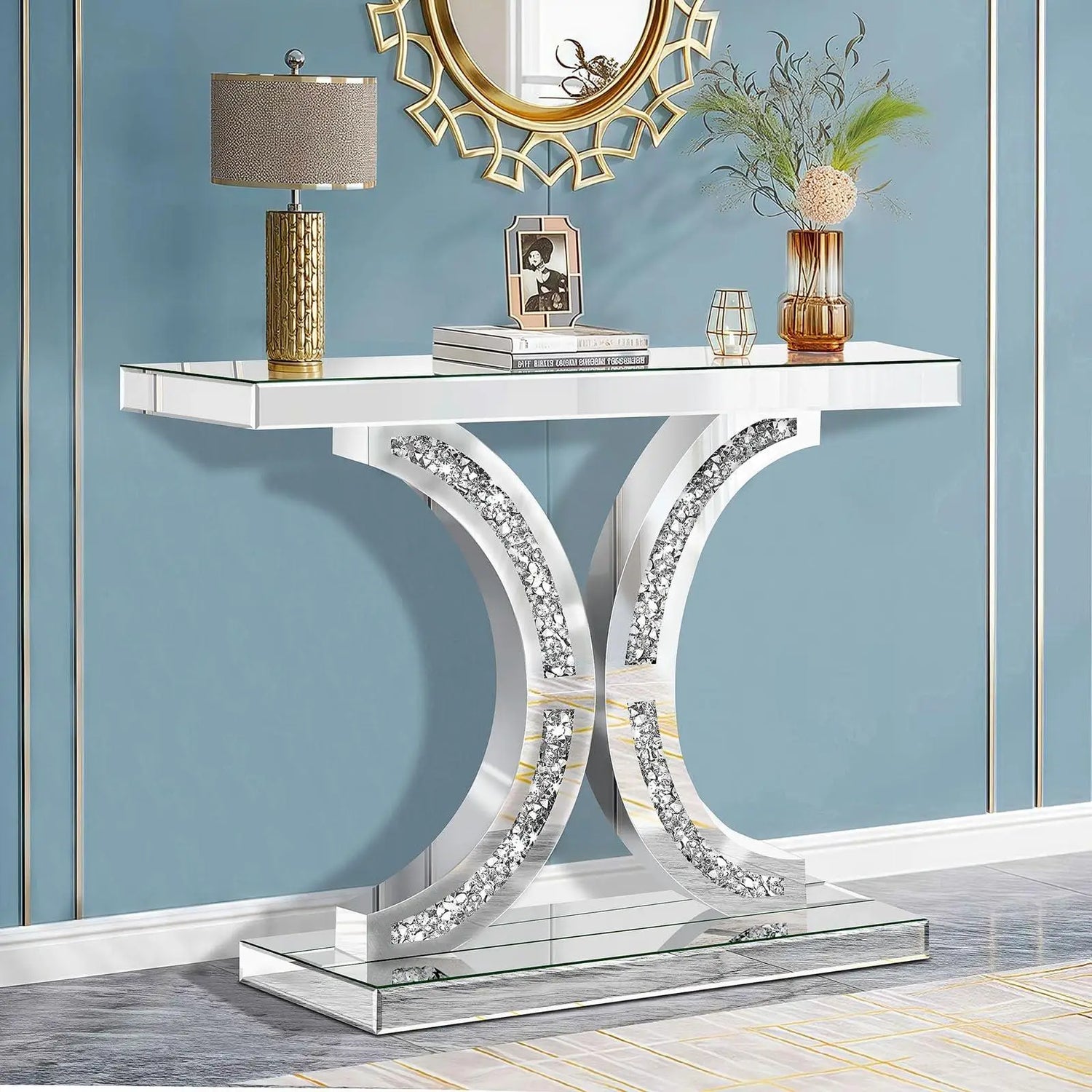 Decorative console table with mirror surface, lamp, and decorative items against a blue wall.