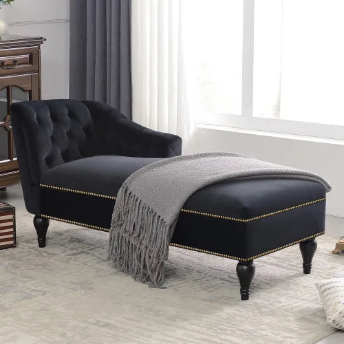 Black tufted chaise lounge with a gray blanket in a living room setting.
