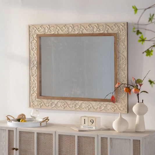 Decorative mirror with intricate frame on a wall above a cabinet.