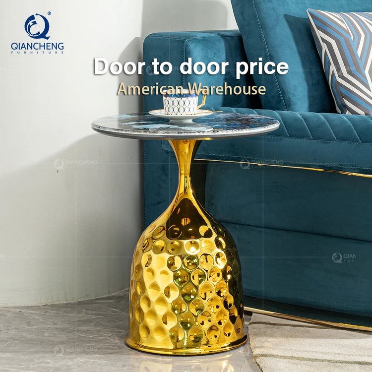 Gold side table with marble top next to a blue sofa in a living room setting.