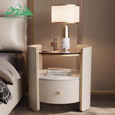 Modern nightstand with lamp and decor items next to a bed