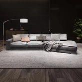 Gray sectional sofa in a modern living room with a dark wall and wooden floor.