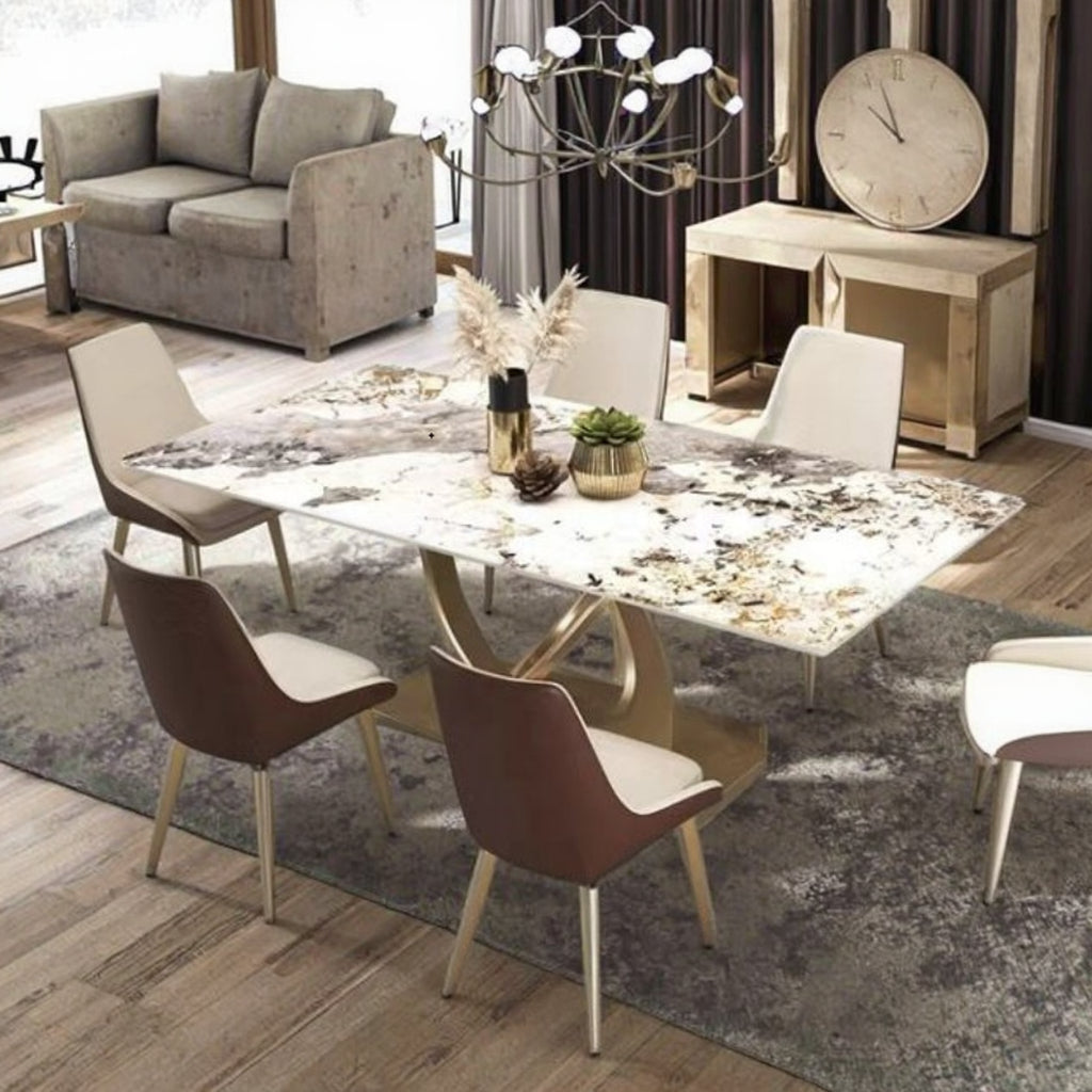 A modern dining room setup featuring a rectangular marble-patterned dining table with gold-tone legs, surrounded by six contemporary chairs in brown and cream upholstery, placed on a gray area rug in a styled living space.