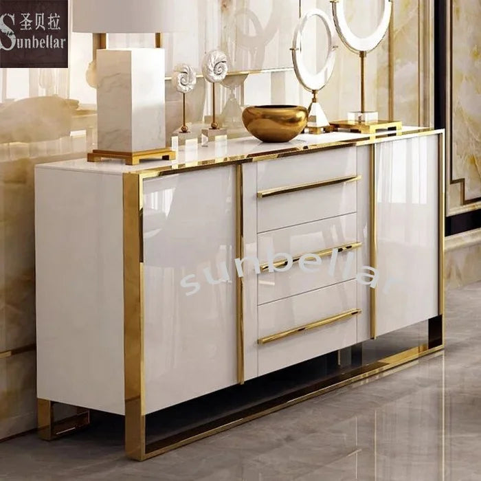 Gold stainless steel console cabinet with tempered glass top and white drawers in an elegant entryway.