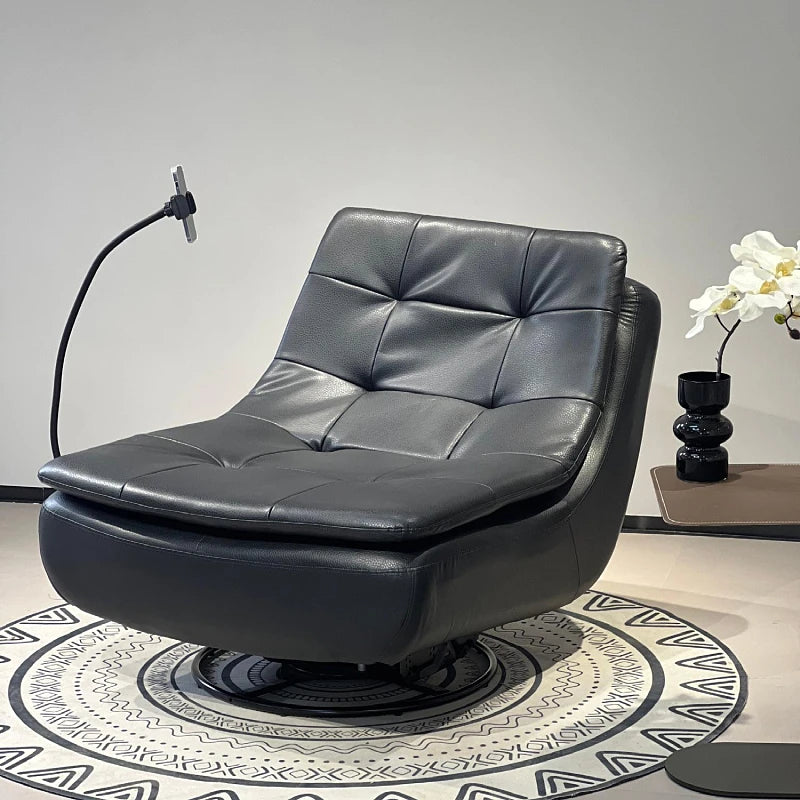 A modern black leather swivel lounge chair with tufted back cushions, shown in a styled interior setting with a patterned rug, a black floor lamp, and a side table with white flowers.