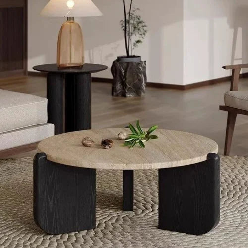 Round coffee table with marble top and black cylindrical legs in a living room setting.