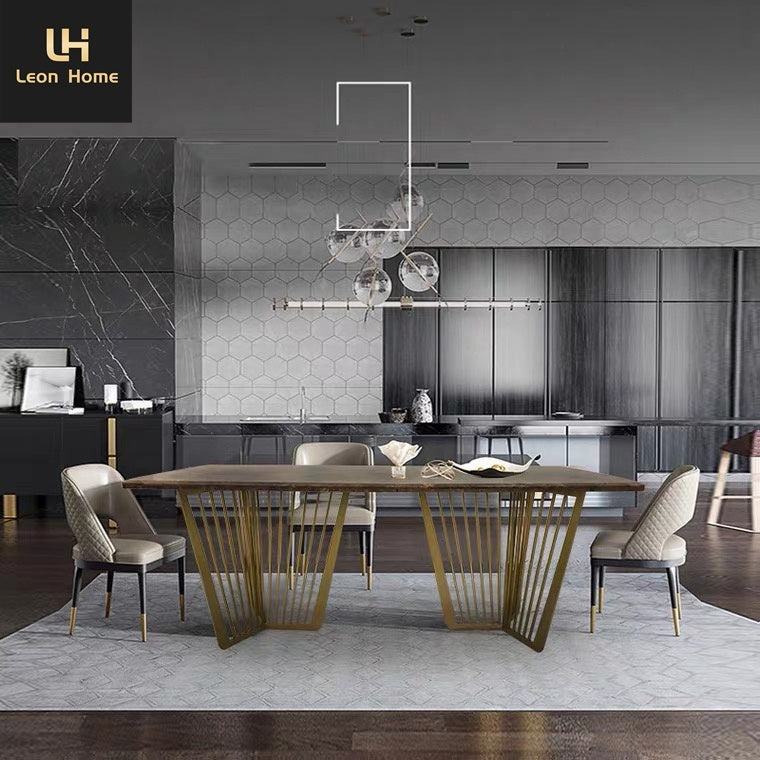 A modern dining room setup featuring a rectangular wooden dining table with distinctive gold metal slatted legs, surrounded by four upholstered dining chairs. The scene is set in a contemporary kitchen with dark cabinets, a geometric tiled backsplash, and a matching geometric area rug.