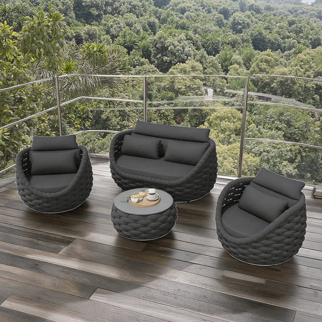4-Piece outdoor aluminum sofa set dark gray on a patio with lush greenery in the background.