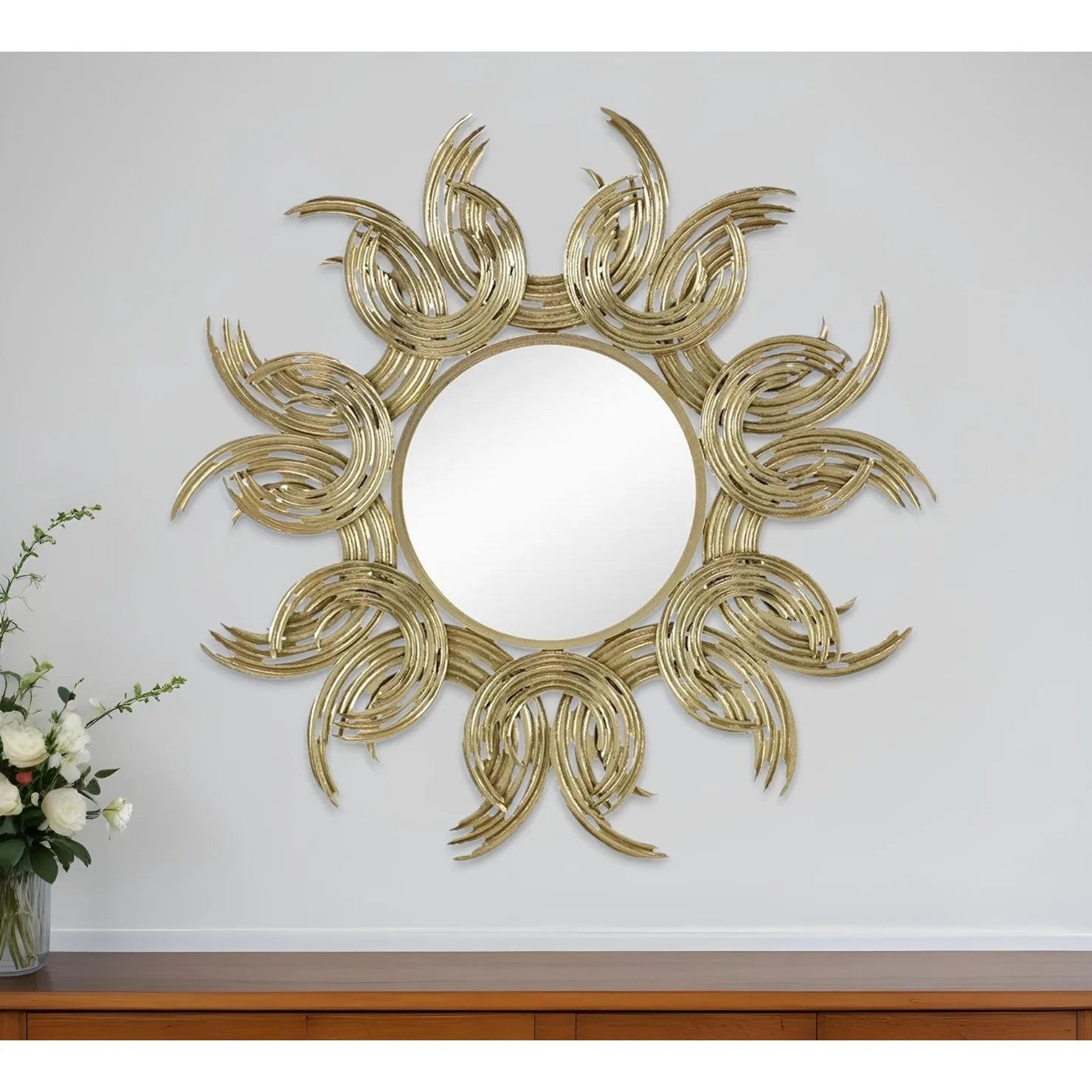 Decorative wall mirror with sunburst design on a white wall.
