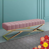 Pink upholstered bench with gold metal frame against a teal wall