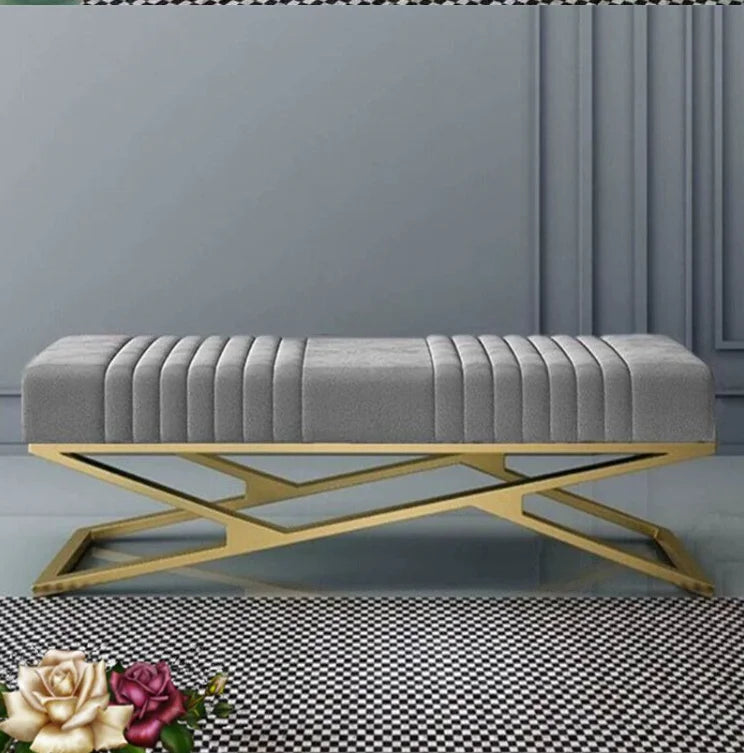 Modern tufted velvet bench with golden stainless steel base in elegant interior setting.