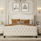 Decorative bedroom with tufted bed, framed pictures, and wall lights.