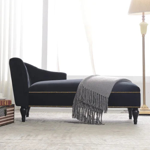 Black upholstered bench with a gray blanket in a room with white walls and a lamp.