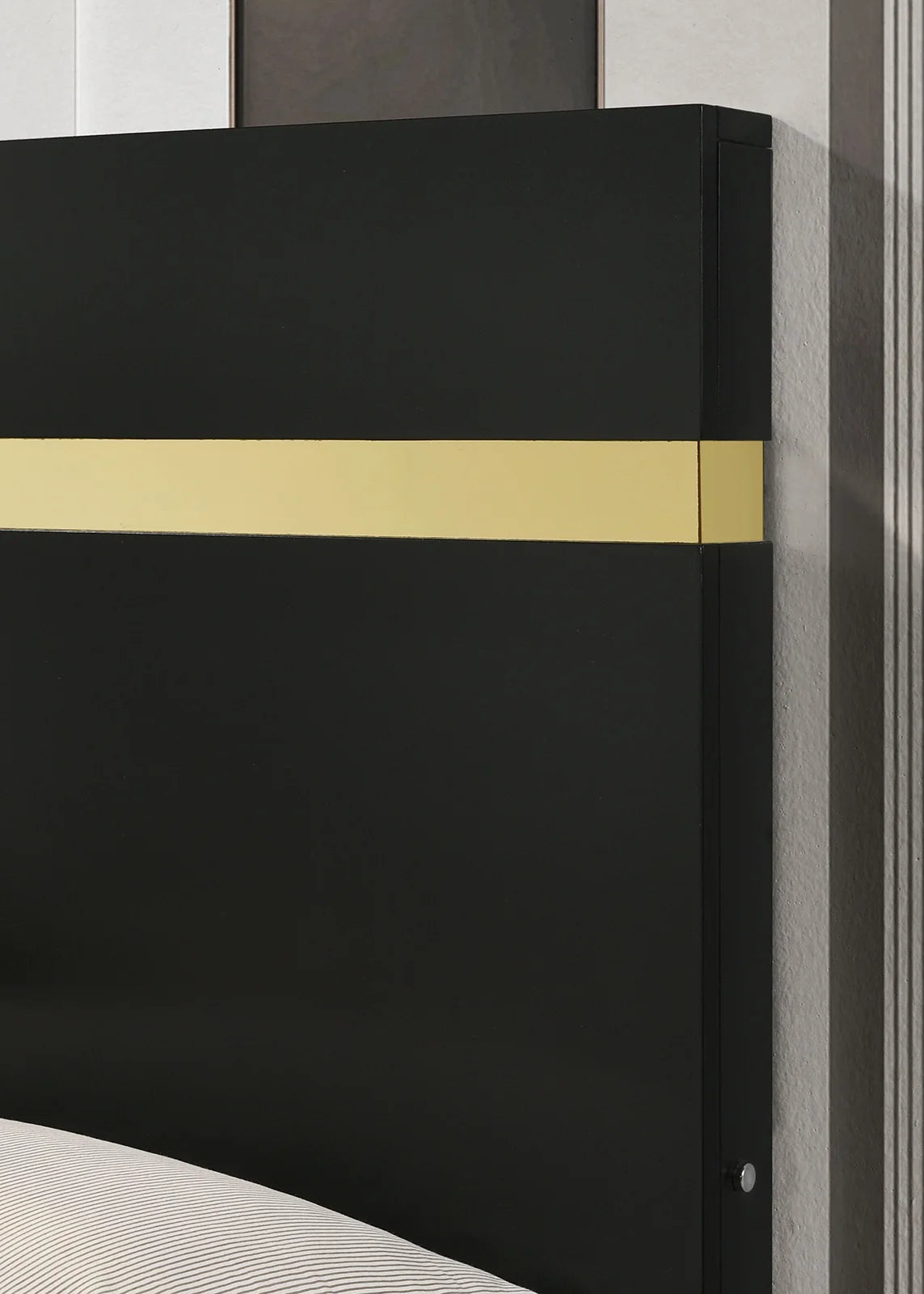 Close-up of modern king bedroom set with LED lighting featuring a black headboard and gold acrylic trim.