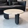 Round marble coffee table with black metal frame on a light-colored floor.