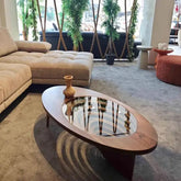 Modern living room with a beige sectional sofa, reflective coffee table, and decorative plants.