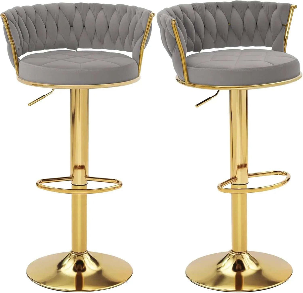 Two gray tufted bar stools with gold metal legs on a white background