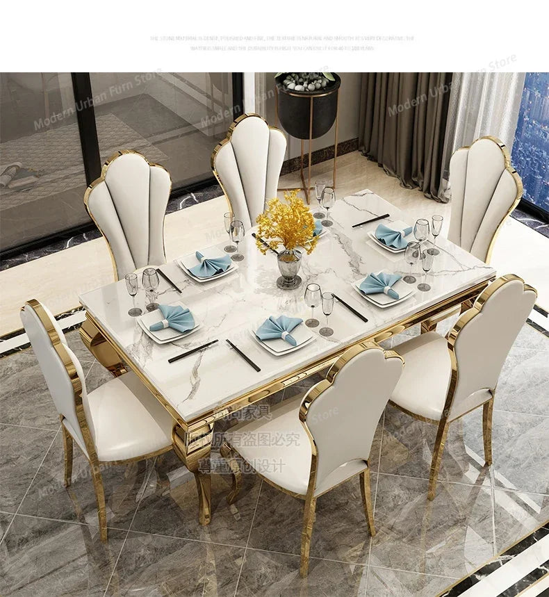 Dining table set with marble surface and gold accents, surrounded by chairs in a modern interior setting.