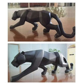 Black panther sculpture on a reflective surface with a blurred indoor background