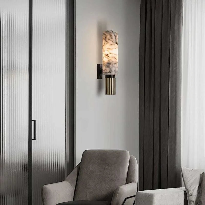 Modern wall sconce with marble-like finish in a room with gray armchair and curtains.