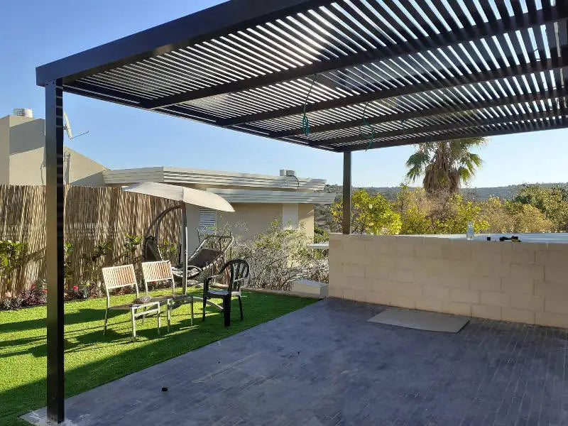 Patio with pergola, chairs, and outdoor furniture under a clear blue sky.