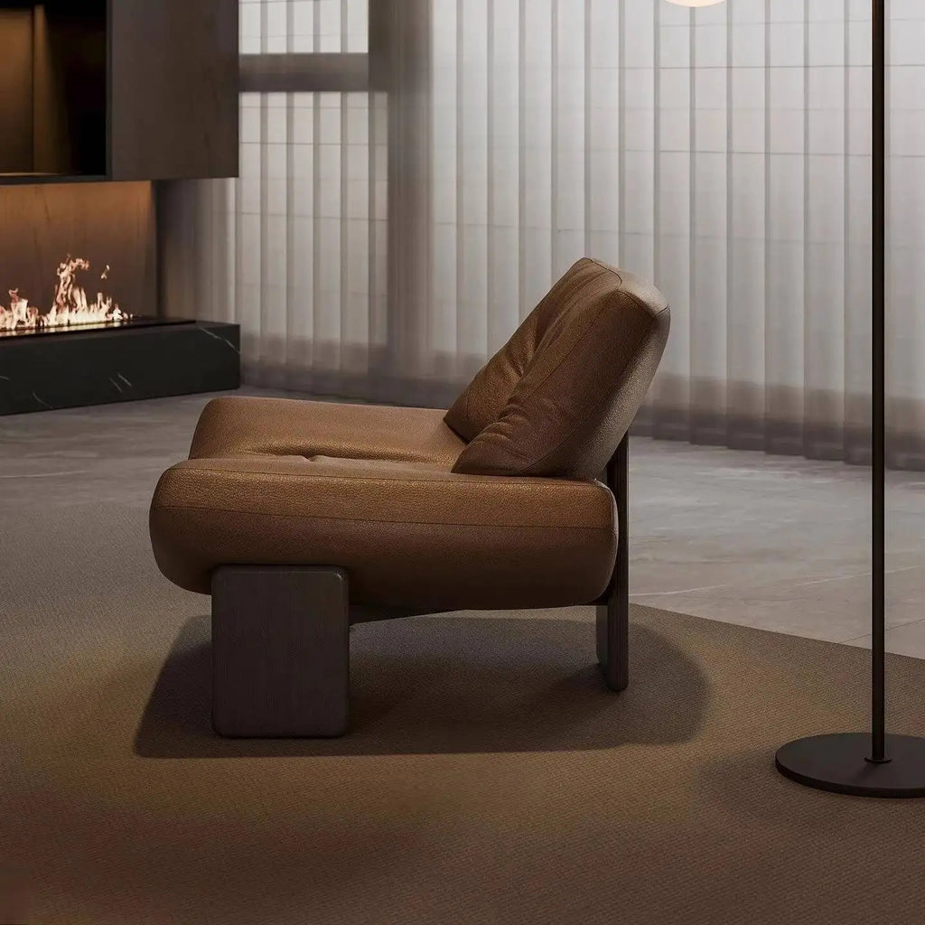 Italian leather single seater sofa chair in a modern living room setting with a cozy fireplace.