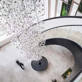 Crystal chandelier hanging above a spiral staircase in a modern building.