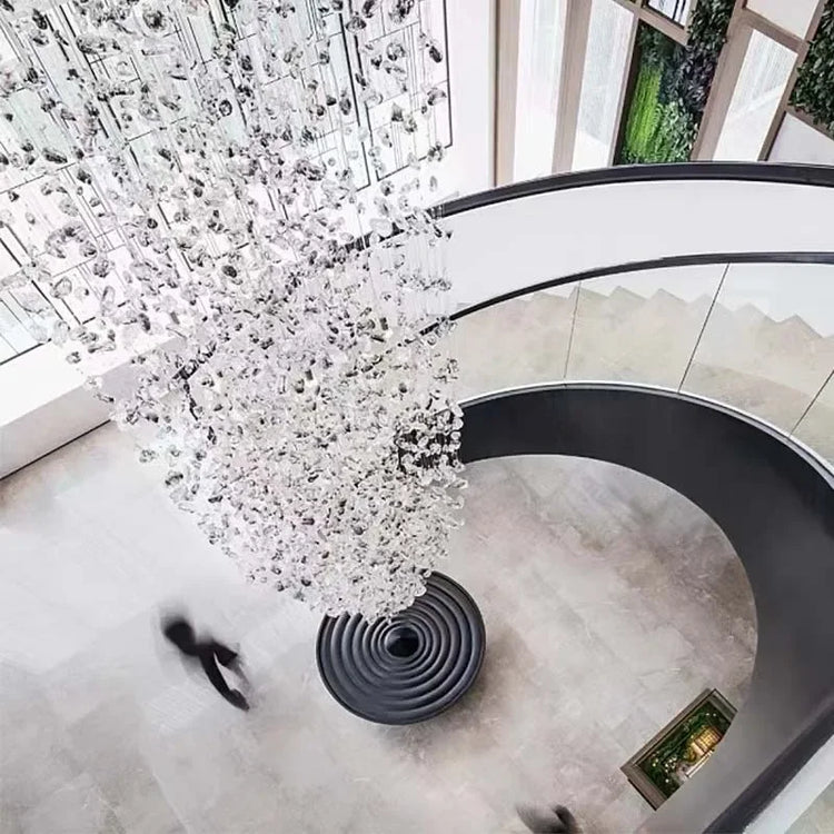Crystal chandelier hanging above a spiral staircase in a modern building.