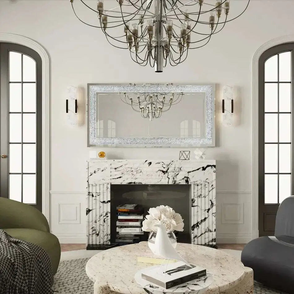 Large silver frameless mirror with crystal rhinestone and diamond border above marble fireplace in elegant living room