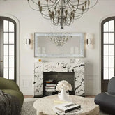 Large silver frameless mirror with crystal rhinestone and diamond border above marble fireplace in elegant living room