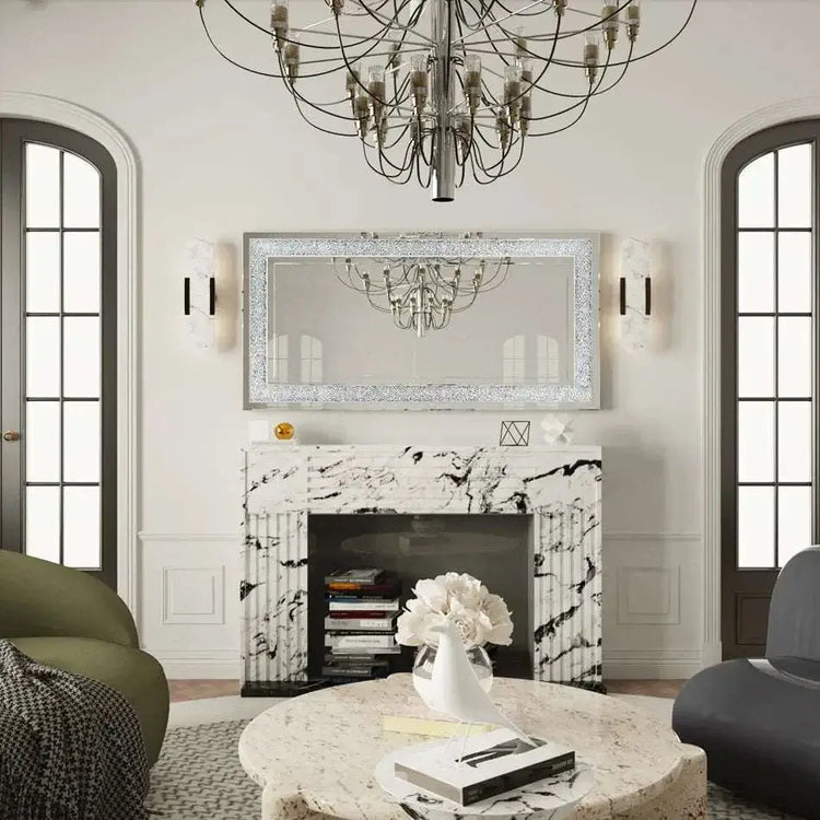 Large silver frameless mirror with crystal rhinestone and diamond border above marble fireplace in elegant living room