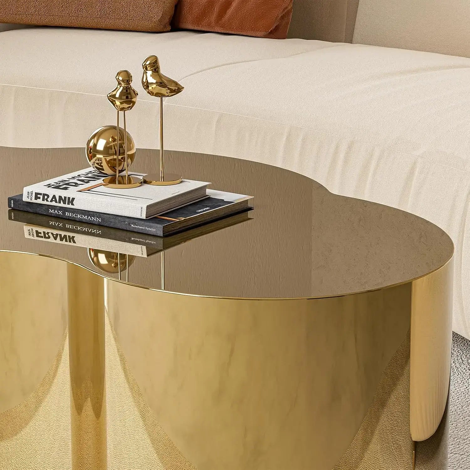 Gold stainless steel coffee table with cloud design, accented with decorative items on the surface.