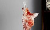 Glass perfume bottle shaped like a dress on a gray background