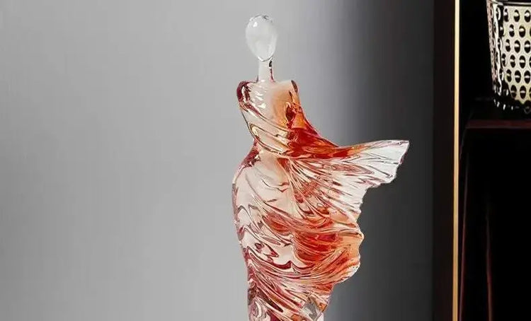 Glass perfume bottle shaped like a dress on a gray background