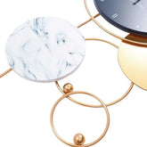 Close-up view of large gold metal wall clock showcasing modern design with marble and gold accents.