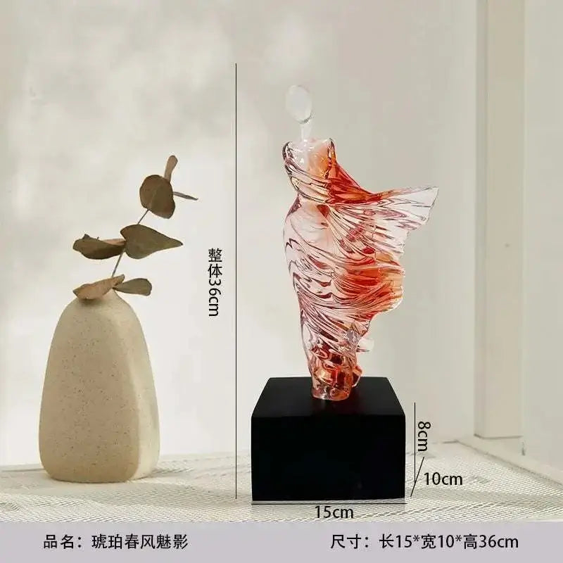 Decorative glass sculpture on a black base with measurements, next to a beige vase.