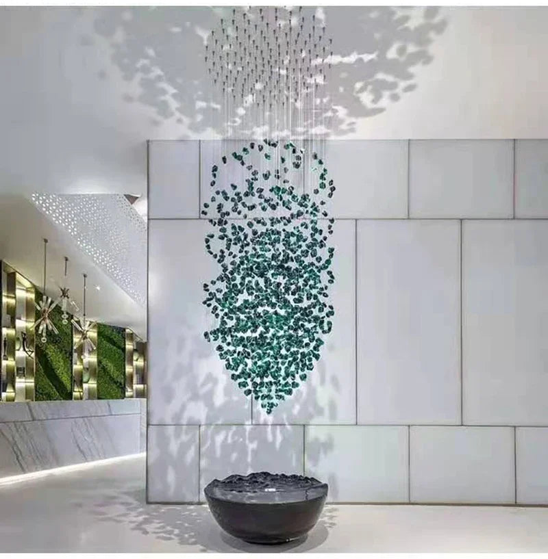 Modern interior design with a chandelier, water feature, and green wall art.