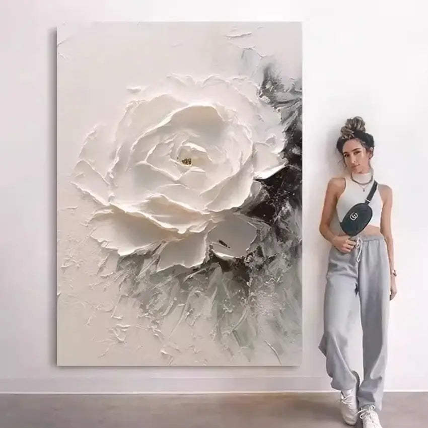Woman standing next to a large abstract painting of a white flower